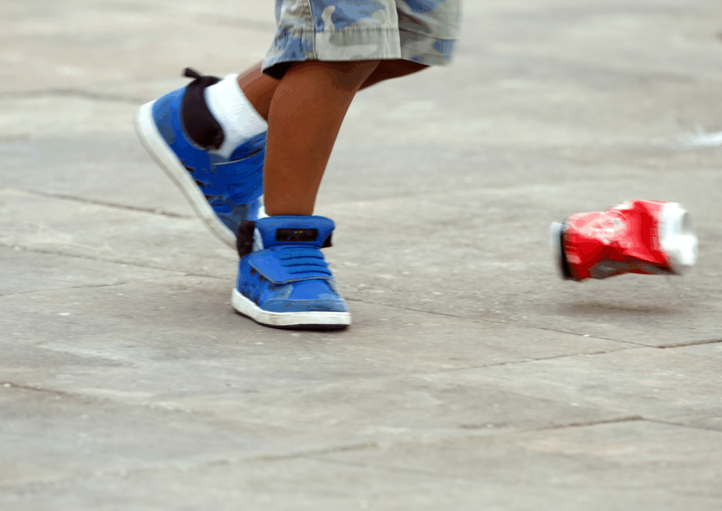 A kid kicking a soda can.