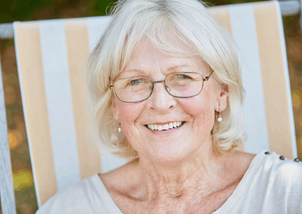An older woman with glasses smiling at the camera.