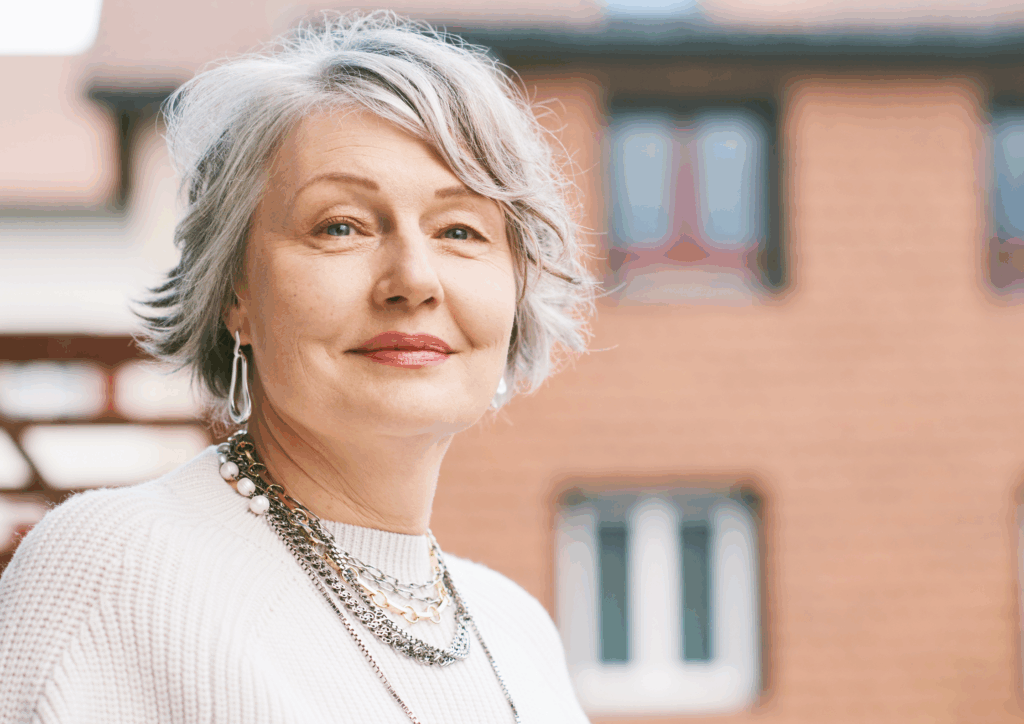 An older woman with a necklace looking back toward the camera.